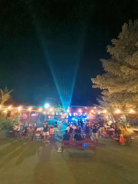 Sinar lampu panggung membentang ke langit malam di atas pengunjung taman.
